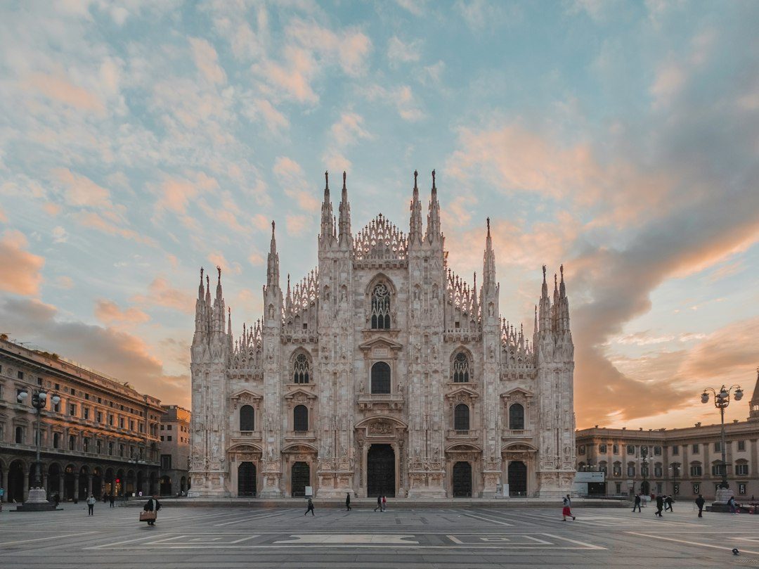 The Duomo di Milano cathedral in Milan under a soft orange and blue sky