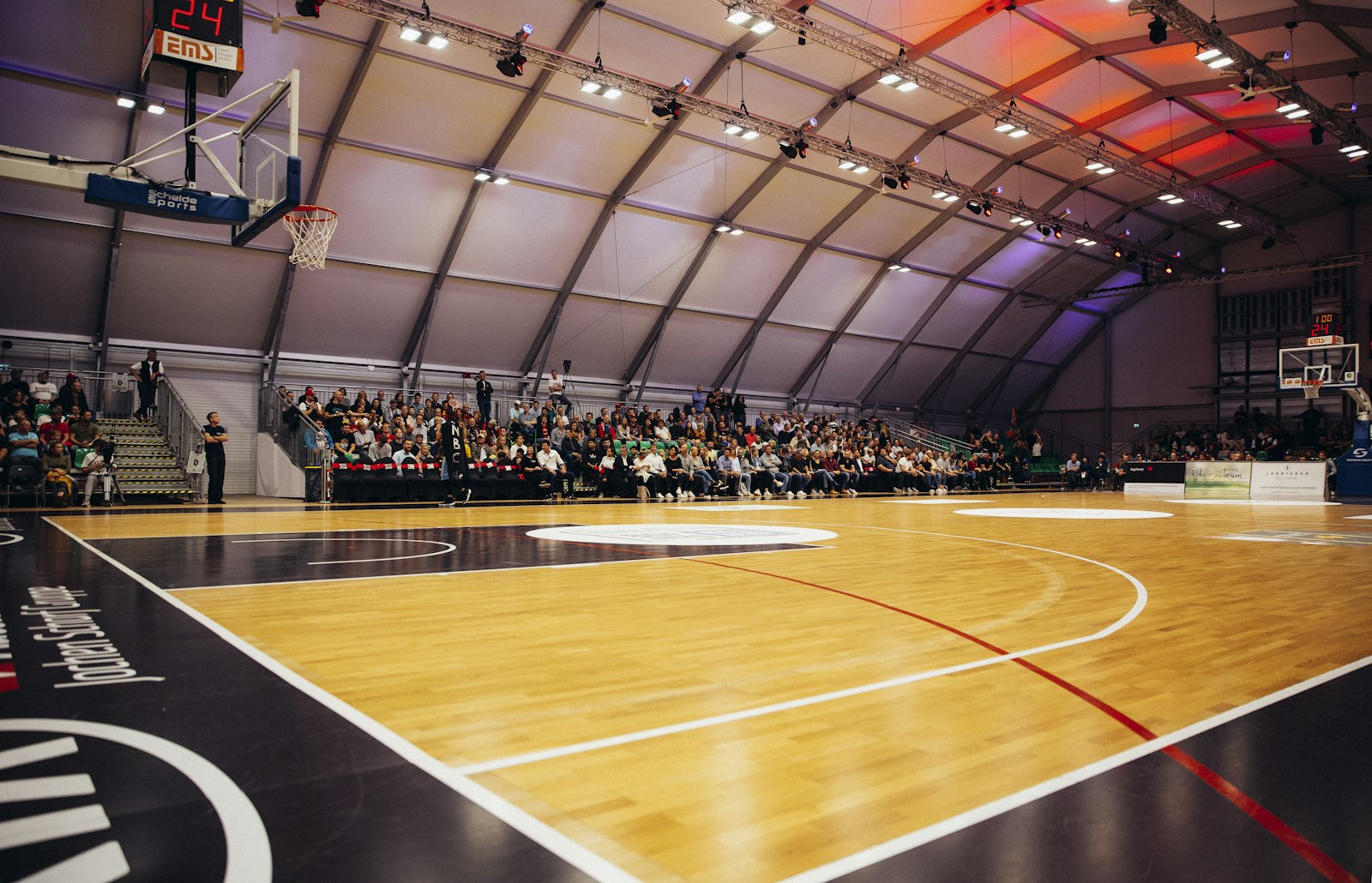 Campo da basket in parquet in un palazzetto con il pubblico in tribuna