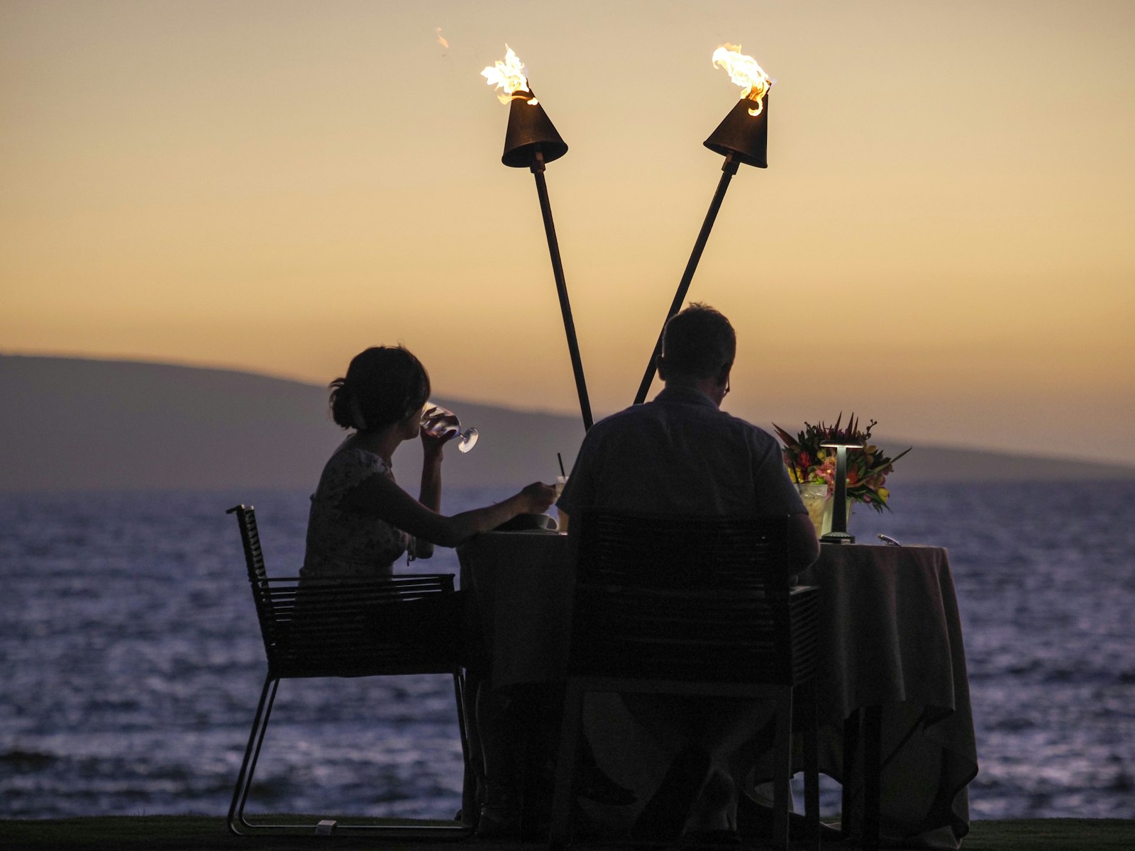 Una coppia a cena al tramonto, con due torce accese