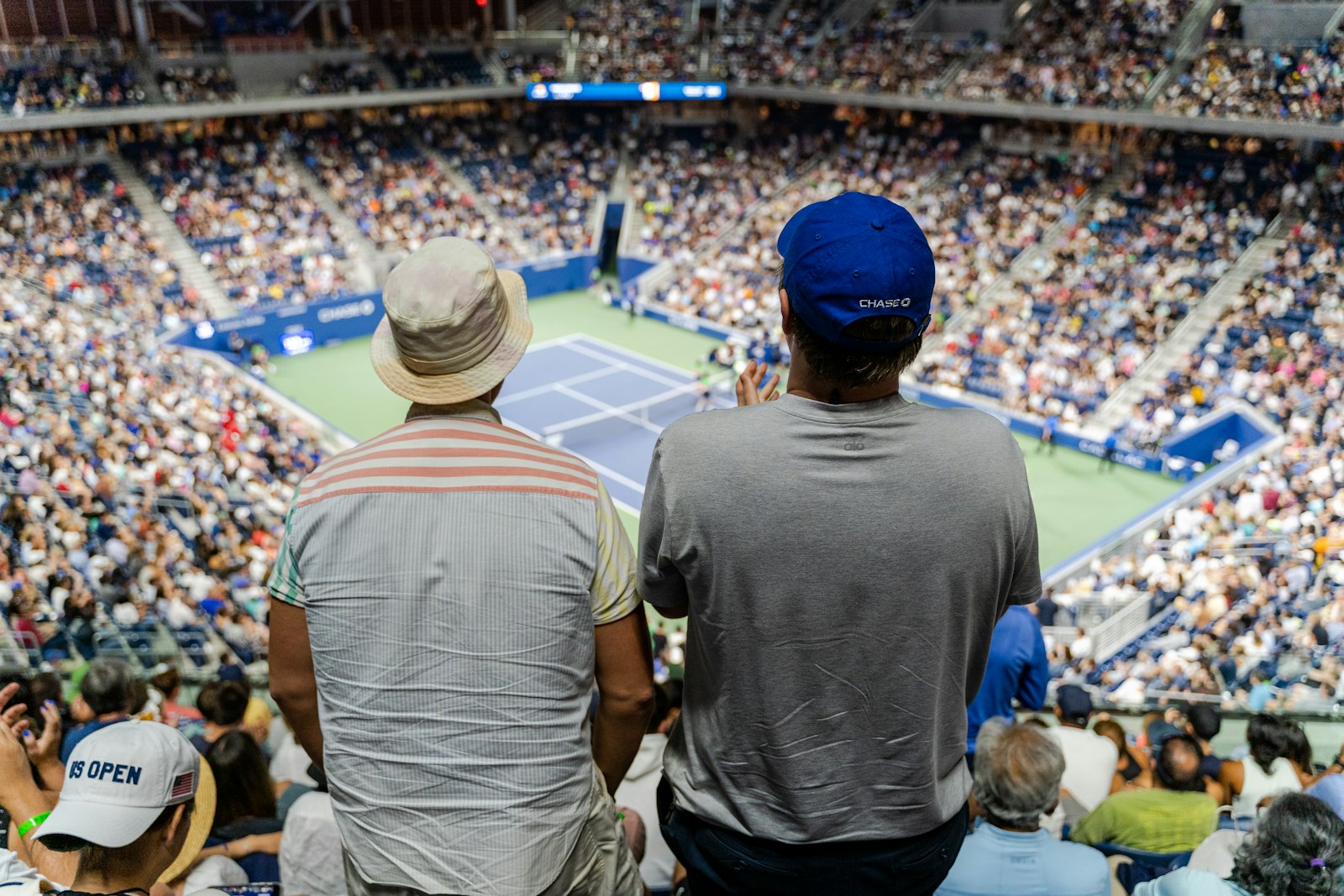 Spettatori in piedi sugli spalti di uno stadio di tennis durante un incontro